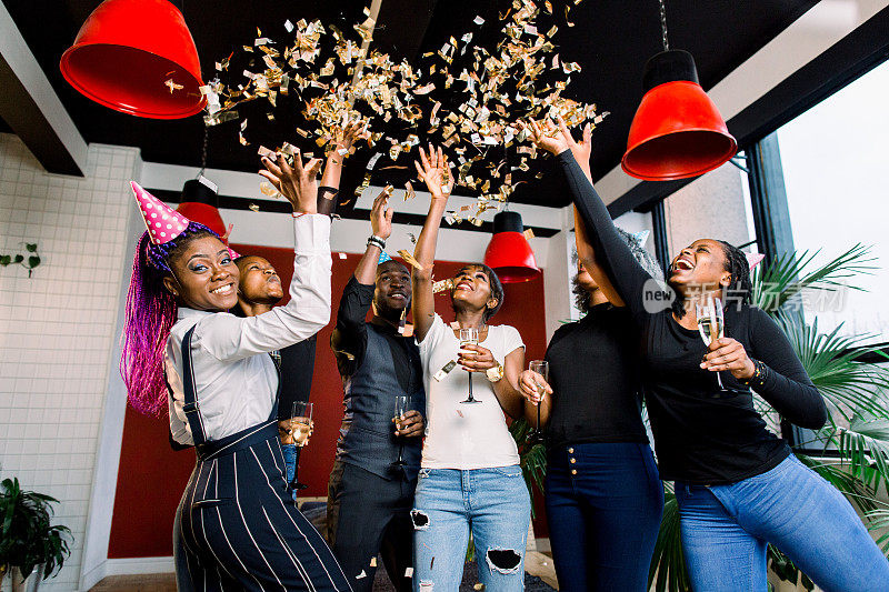 一群非洲人手里拿着饮料庆祝派对，五彩纸屑四处飞舞