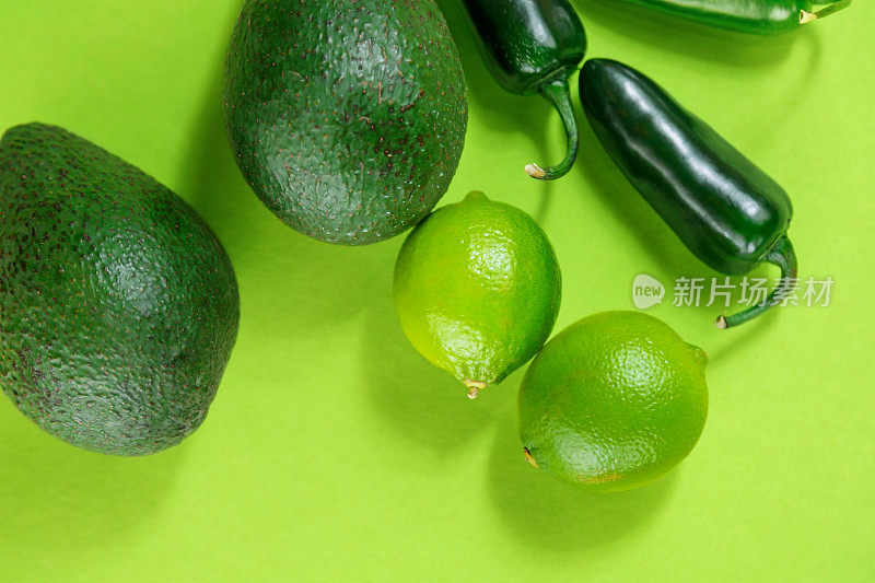 鳄梨，酸橙和绿色辣椒在绿色背景特写
