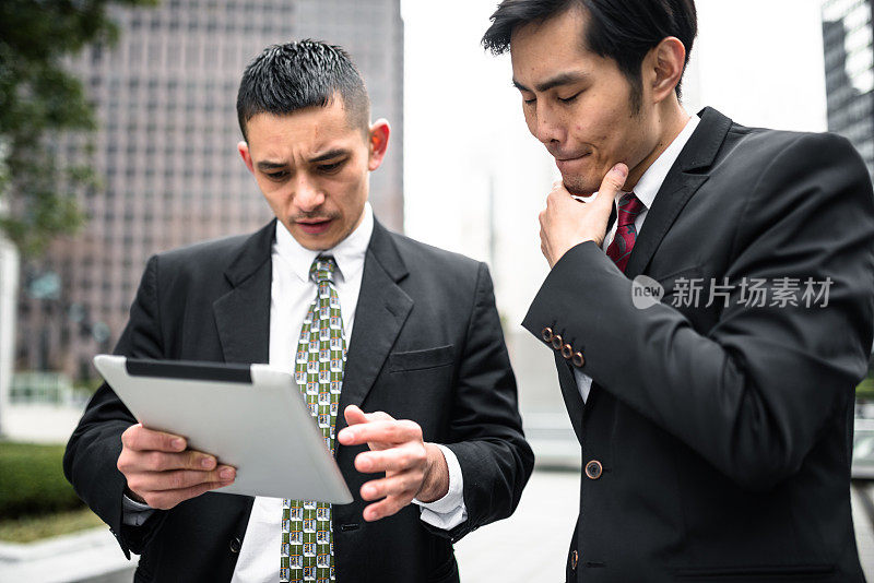 两个亚洲商人在平板电脑上读取数据
