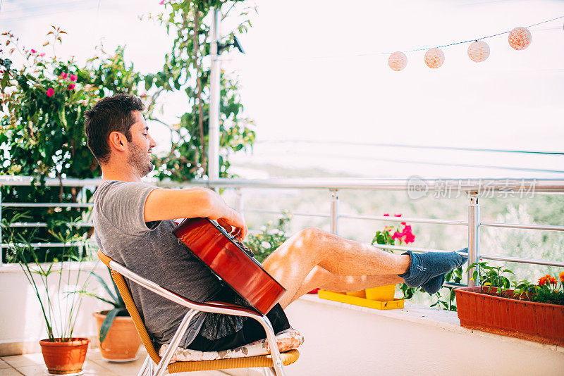 封锁期间，一名男子在阳台上在线学习吉他