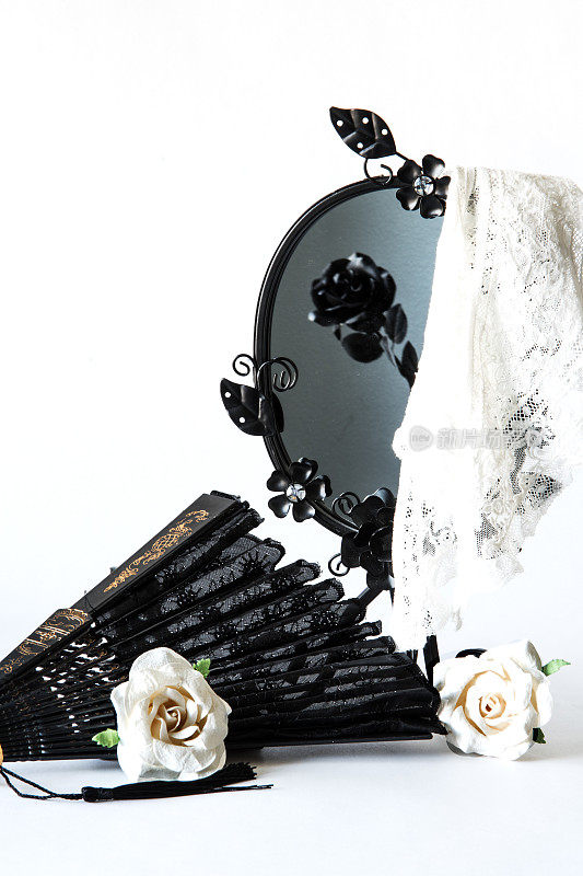 复古的黑色镜子与白色蕾丝覆盖和纸玫瑰和手扇在白色的背景。葬礼，哀悼和悲伤的概念