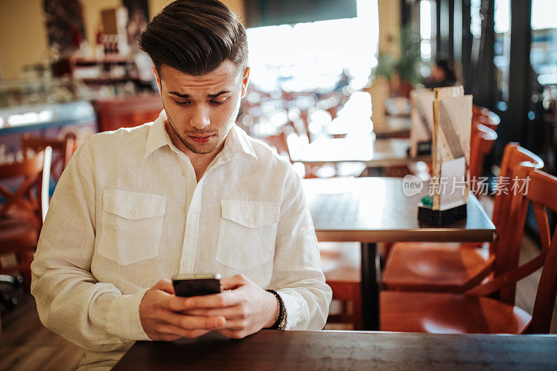 一名年轻人在城市咖啡馆里使用智能手机