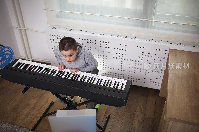 一个男孩在跟他的教授上在线钢琴课