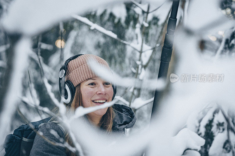 年轻女子带着音响设备徒步穿越雪域森林