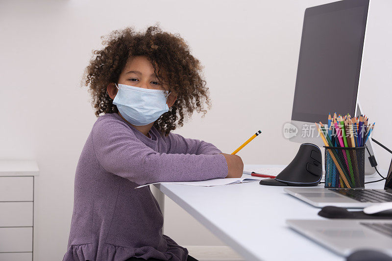 带着口罩的孩子在网上学习。远程学习。远程学习。冠状病毒大流行的概念。