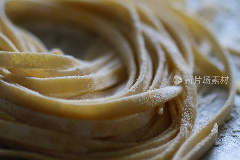 近距离拍摄的自制意式扁面，将意大利面面团撒上面粉，放在撒了面粉的木砧板上晾干，这是意大利美食