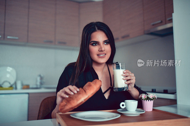 女性吃牛角面包早餐