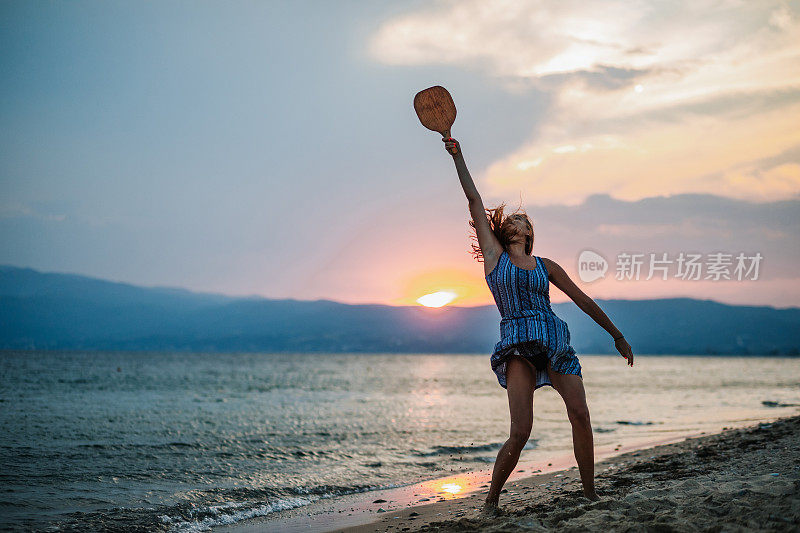 一个年轻女子在海滩上玩划桨球