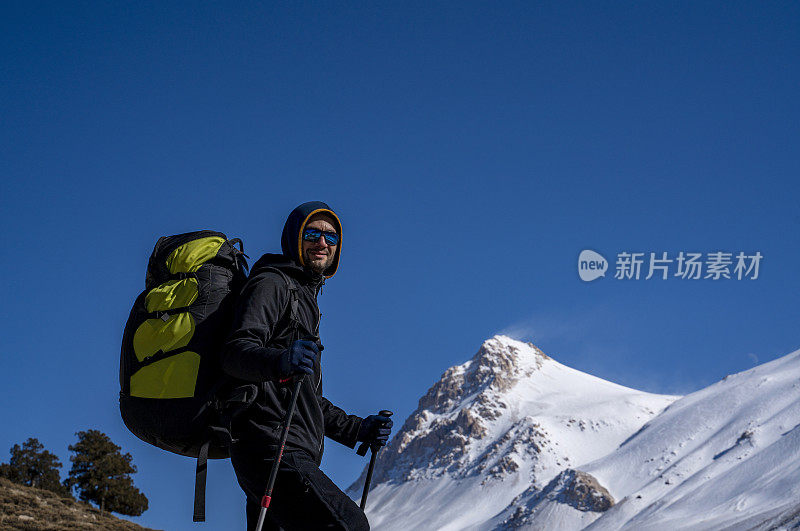 冬天背着降落伞背包在山上徒步旅行的人