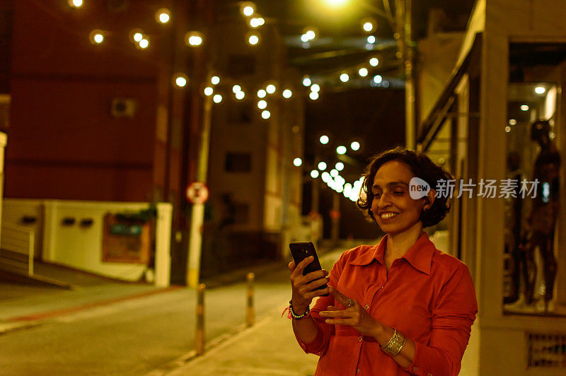 一个女人在灯火通明的街道上用手机