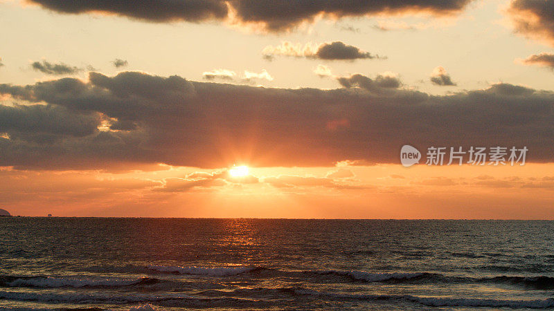 太阳在海上落下时的延时摄影。日落是橙色的，景色是极好的。这是一个神奇的时刻