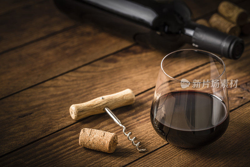 在木桌上用一个软木塞和一个螺旋盖盛满葡萄酒的玻璃杯