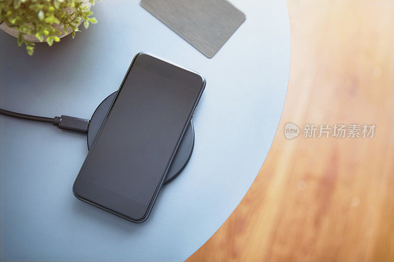 现代黑色智能手机放在桌子上，旁边是电子芯片门禁卡。高角度的观点。