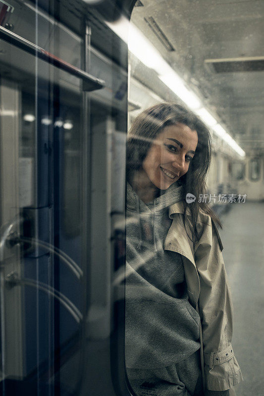 一个穿着米色风衣的女孩坐在地铁车厢里