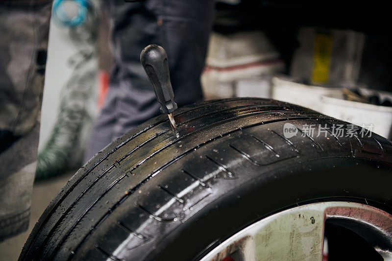 硫化剂固定一个洞，从一个用钉子从一个用过的轮胎在室内汽车修理店