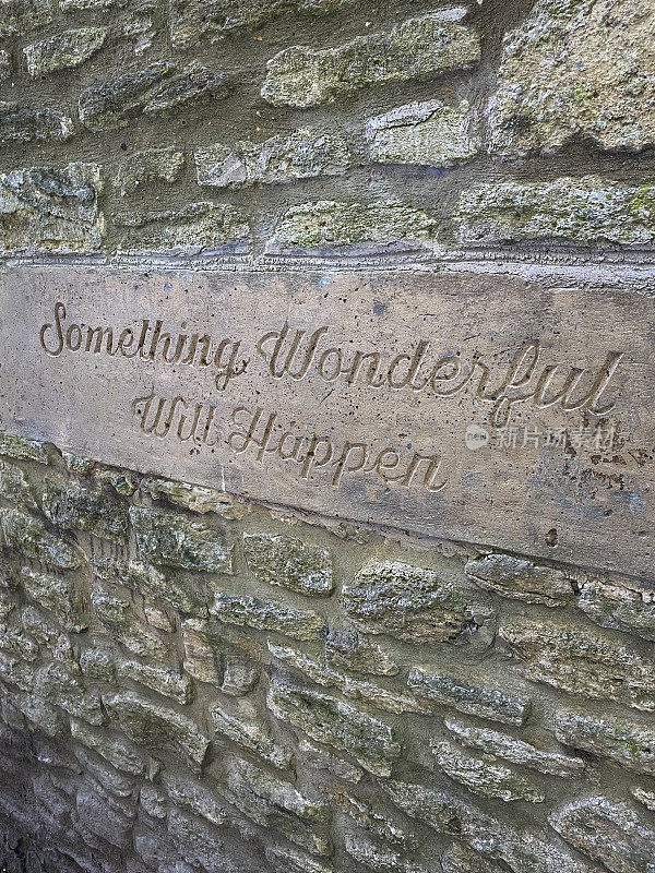 在石头墙上刻着“美好的事情将会发生”的水泥板标识图像