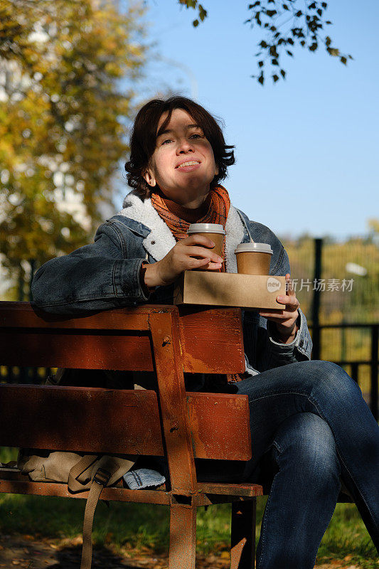 成熟的女人是边喝咖啡边在公园的长椅上等人