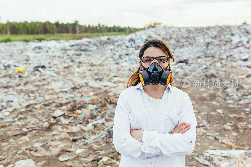 在垃圾填埋场，戴着防护口罩的女科学家正在评估环境污染程度