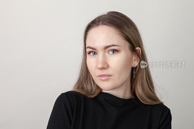一个23岁的棕色头发的女人在灰色背景上的工作室肖像