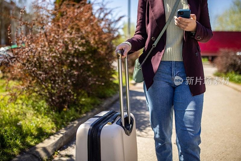 一位面目全非的年轻女子带着行李旅行，同时使用手机