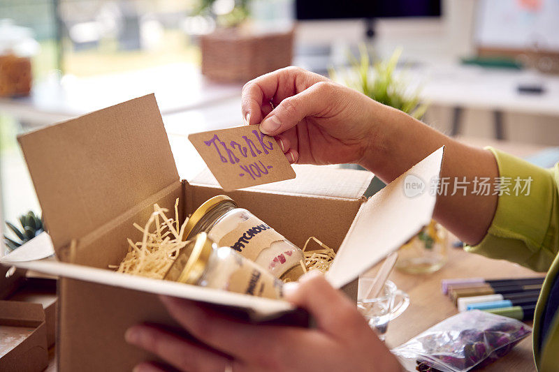 女子经营网上业务从家庭包装和标签精品蜡烛准备航运