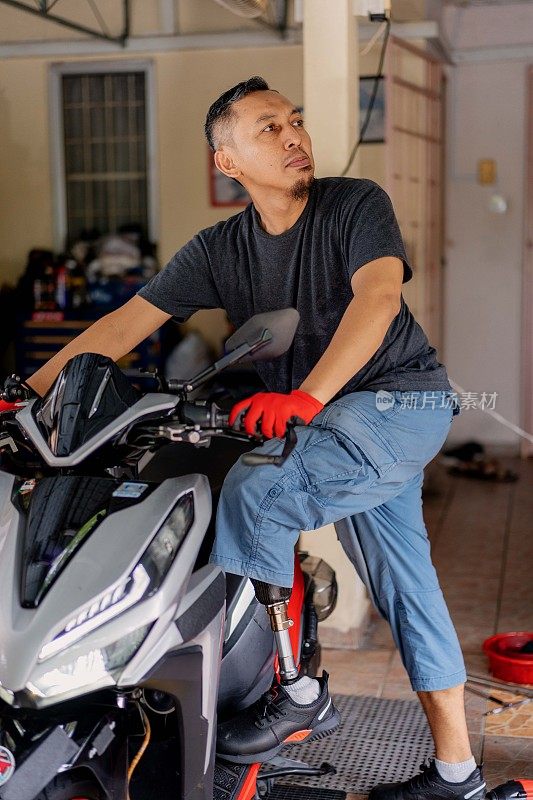 马来西亚一名截肢男子与他的摩托车合影