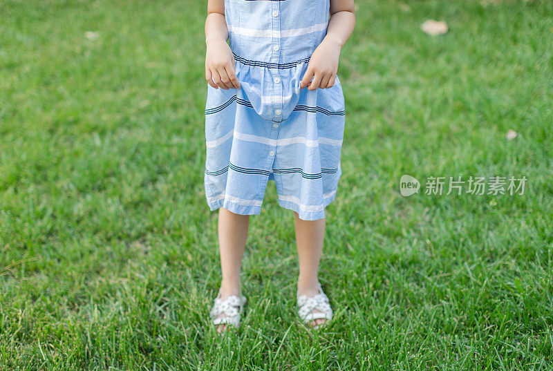 小女孩穿着凉鞋站在草地上