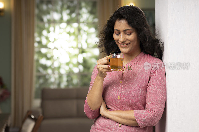 年轻女子喝一杯凉茶在家里股票照片