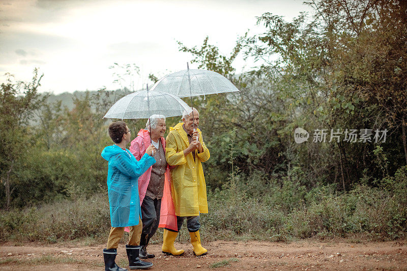 快乐的几代同堂在雨天的大自然中打着伞散步