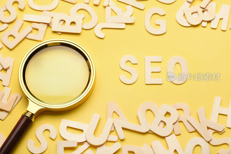 搜索引擎优化的概念。搜索引擎优化SEO字写在黄色背景用放大镜和木制字母