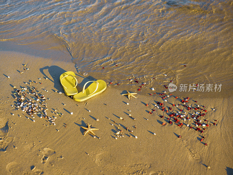 黄色的沙滩拖鞋站在沙滩上。