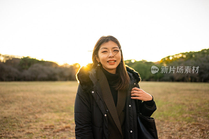 微笑的亚洲妇女站在夕阳下的肖像