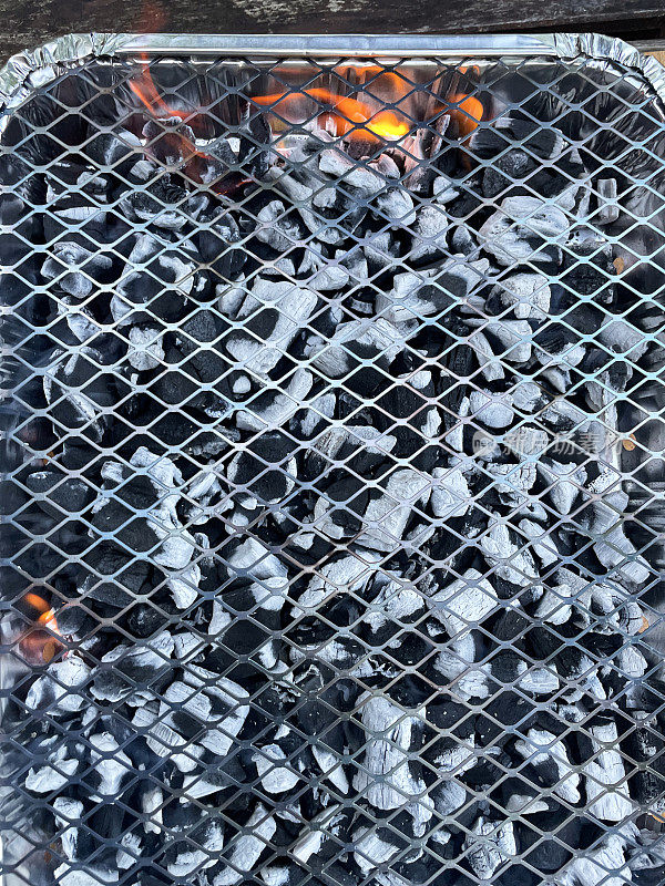 燃烧的煤在一次性铝箔烧烤的特写图像，高架视图