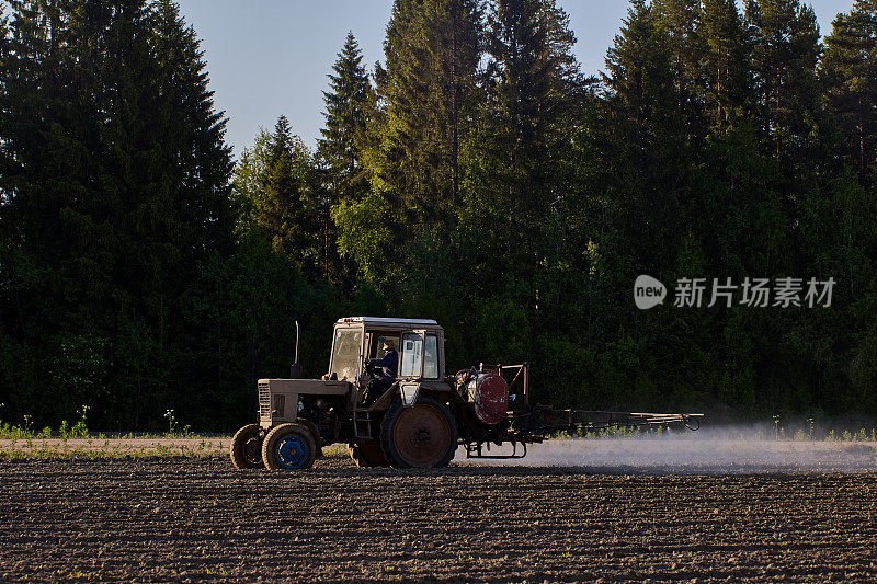 农用拖拉机在吊杆上用喷雾器给马铃薯作物施用除草剂。