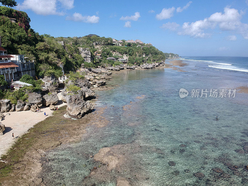 2023年8月，一个阳光明媚的日子，在退潮期间，无人机在巴厘岛乌鲁瓦图的宾金海滩拍摄的照片，周围有餐馆、房子和人们