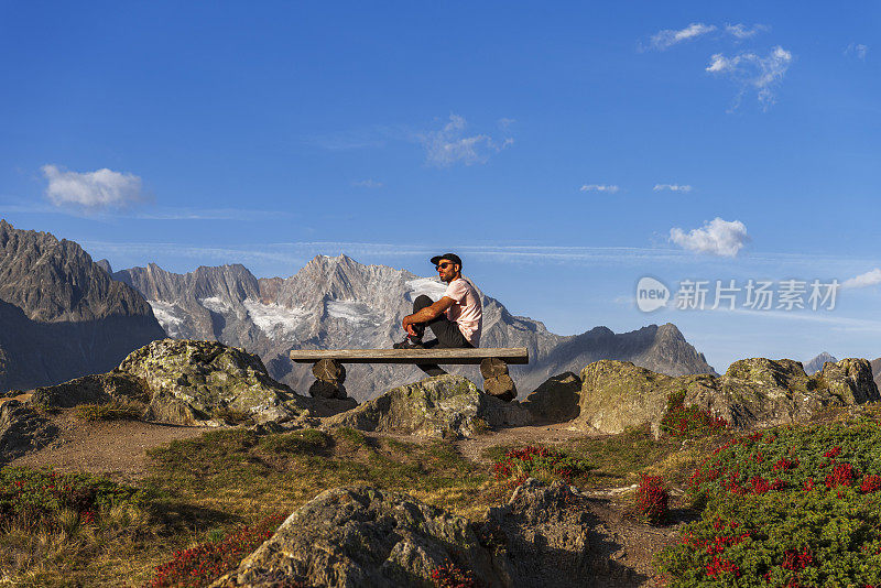 酷酷的高加索人坐在瑞士阿尔卑斯山脉阿莱奇冰川的长凳上