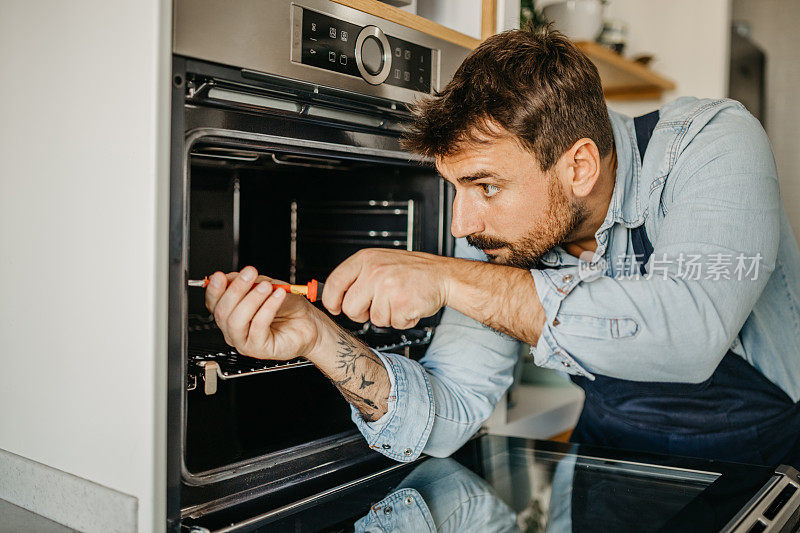 经验丰富的男性杂工将新烤箱无缝集成到厨房设置中，确保房主的无缝功能和有效使用