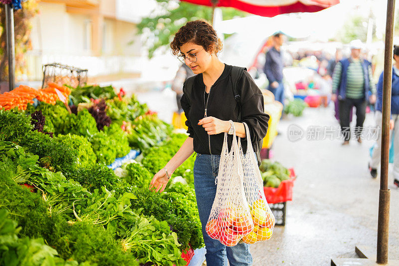 一名妇女在农贸市场拿着网购买水果和蔬菜