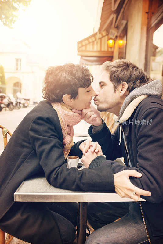 一对相爱的欧洲情侣正要在户外咖啡馆接吻。