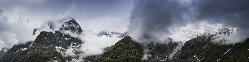 云层盘旋在壮观的岩石山峰和阿尔卑斯冰川之间