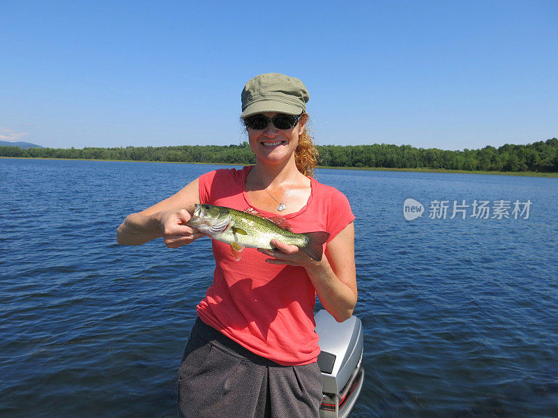 女性30岁持有鲈鱼，球拍湖，纽约阿迪朗达克