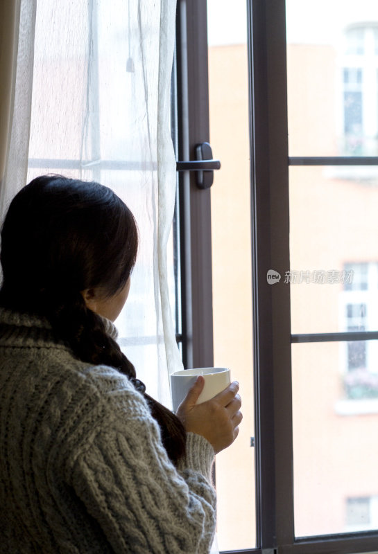 女孩在窗边喝着咖啡，看着窗外