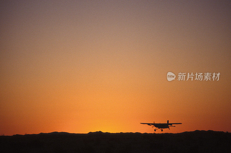 日落时分，一架小飞机降落在沙漠中