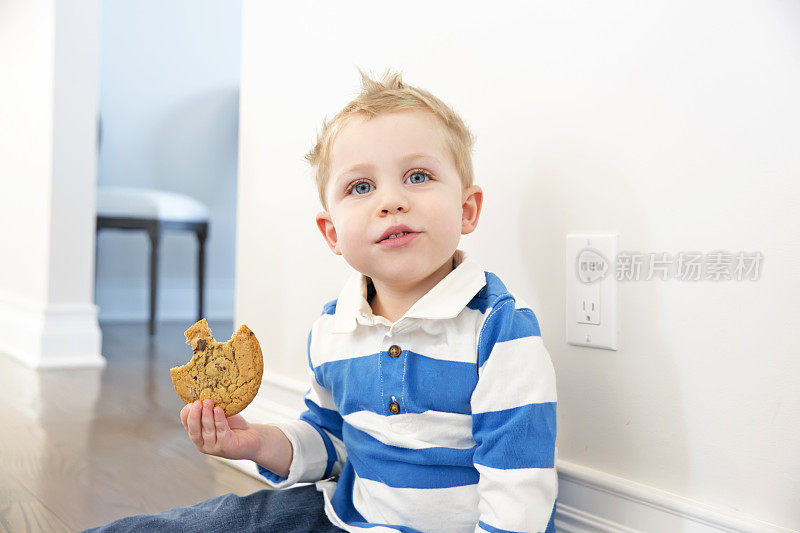 真正的四岁男孩坐在地板上吃饼干