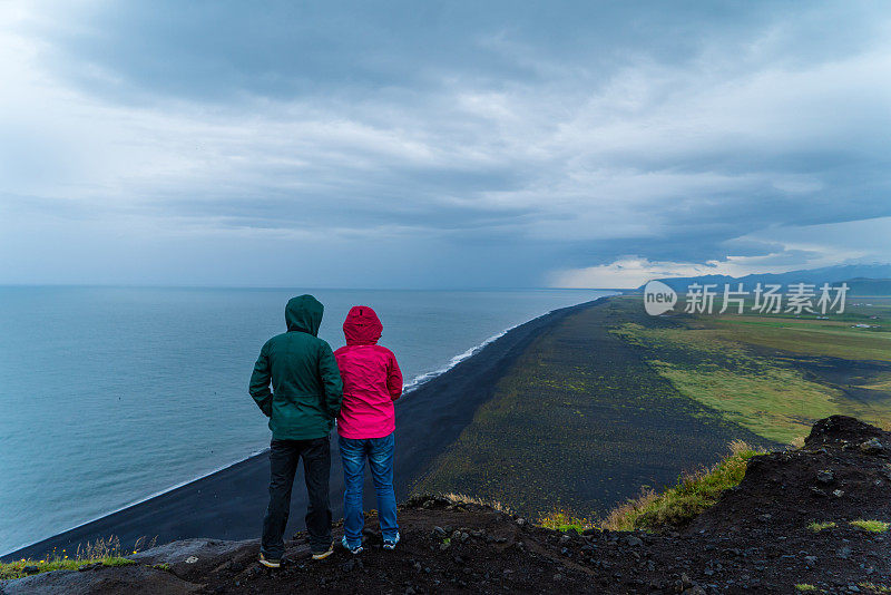 一对年轻夫妇望着远方的大海