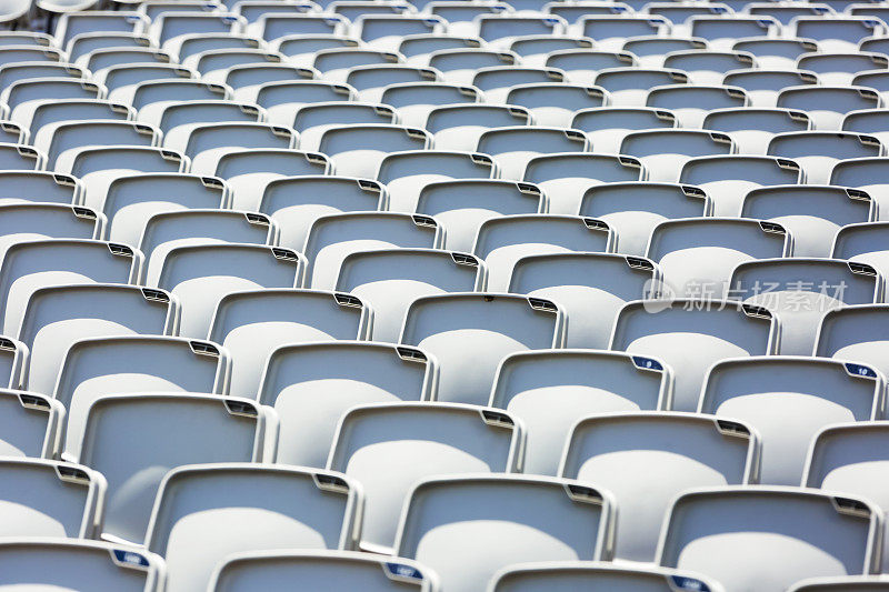 空旷的灰色塑料座椅在阳光下的体育场，拷贝空间