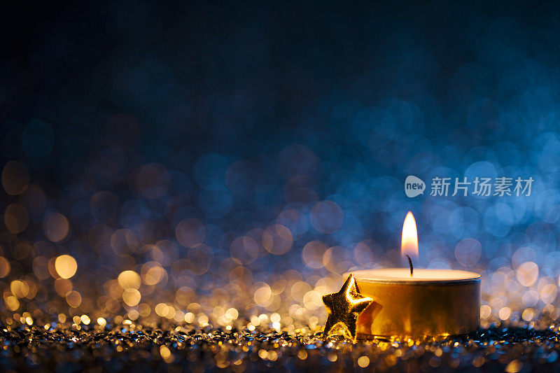 点燃蜡烛散焦蓝色背景-圣诞茶灯