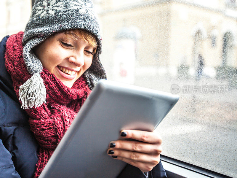 一个十几岁的女学生在公交车上拿着平板电脑