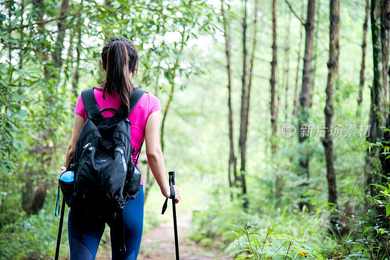 在树林里背着背包的年轻女性徒步旅行者