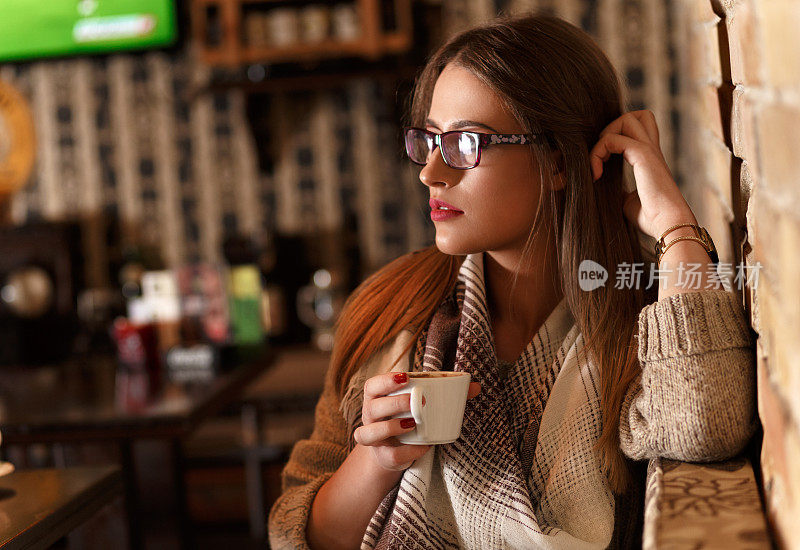 年轻女子坐在咖啡馆里喝着咖啡。